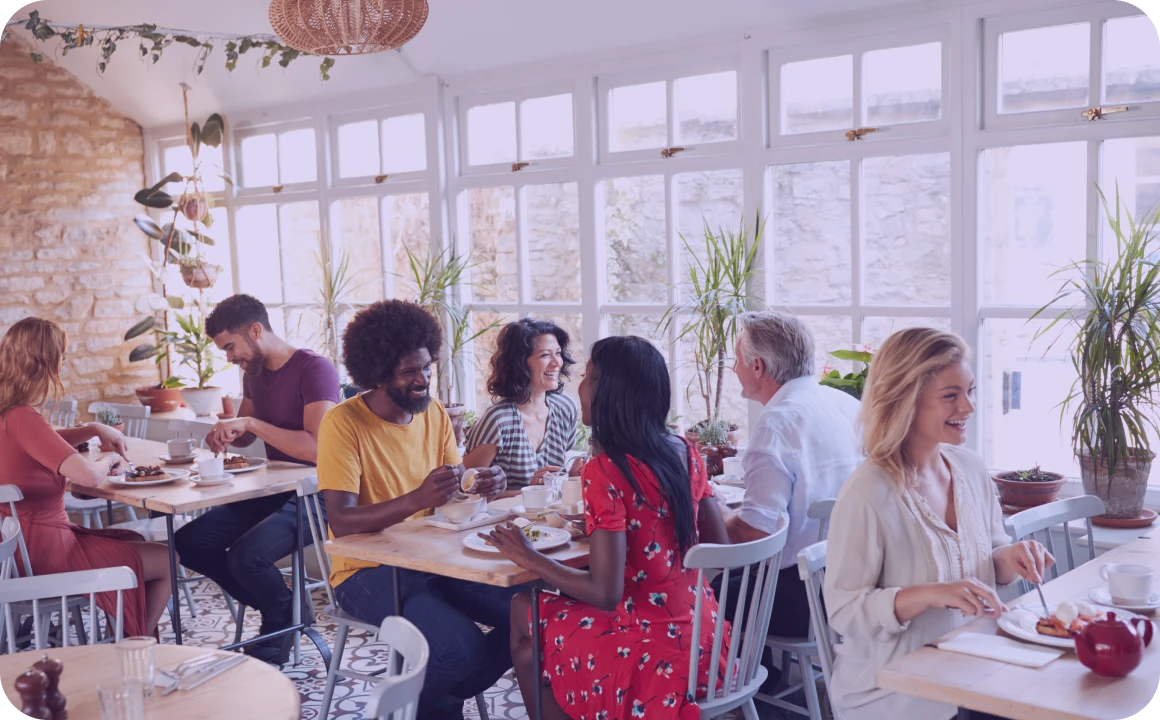 Personen beim Mittagessen in einem Restaurant, das TopMessage als Kommunikationsplattform nutzt.